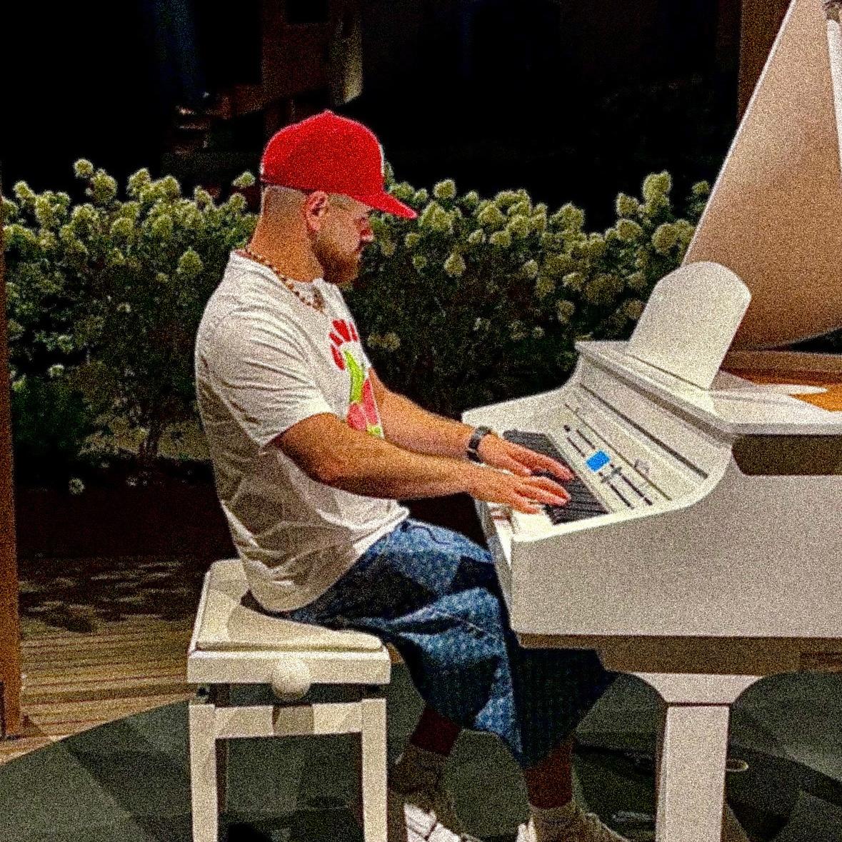 Zheremy sitzt an einem weißen Klavier und spielt